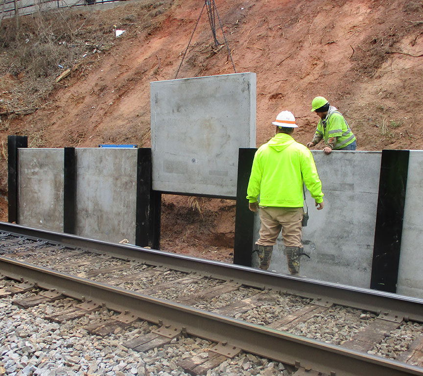 High Point Improvements - Workers place concrete panels for new retaining wall south of Wrenn Avenue